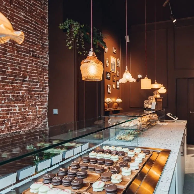 winkelinrichting op maat met witte patisserie toonbank, glazen vitrine met macarons productpresentatie en warm bakkerij winkelinterieur met bakstenen wand en hanglampen