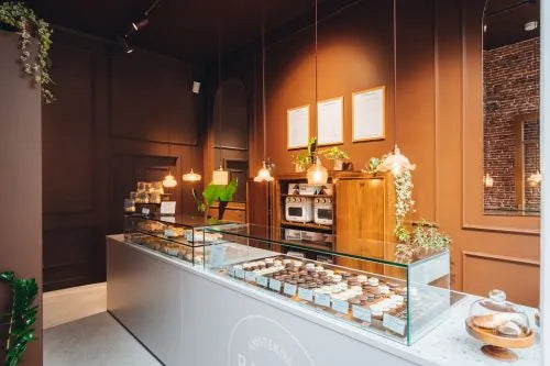 winkelinrichting op maat met glazen vitrine, productpresentatie, warme bruine wandpanelen en moderne patisserie toonbank