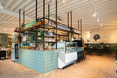 winkelinrichting op maat met groen betegelde bakkerijtoonbank, metalen winkelstelling en productpresentatie in modern bakkerij winkelinterieur