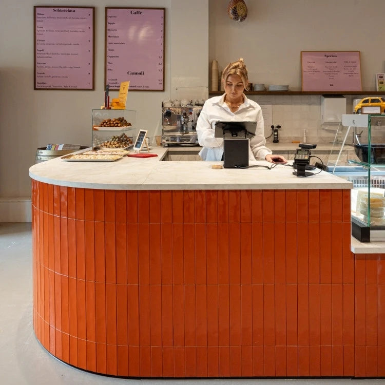 winkelinrichting op maat met ronde oranje betegelde toonbank, wit werkblad en modern horeca winkelinterieur met kassapunt