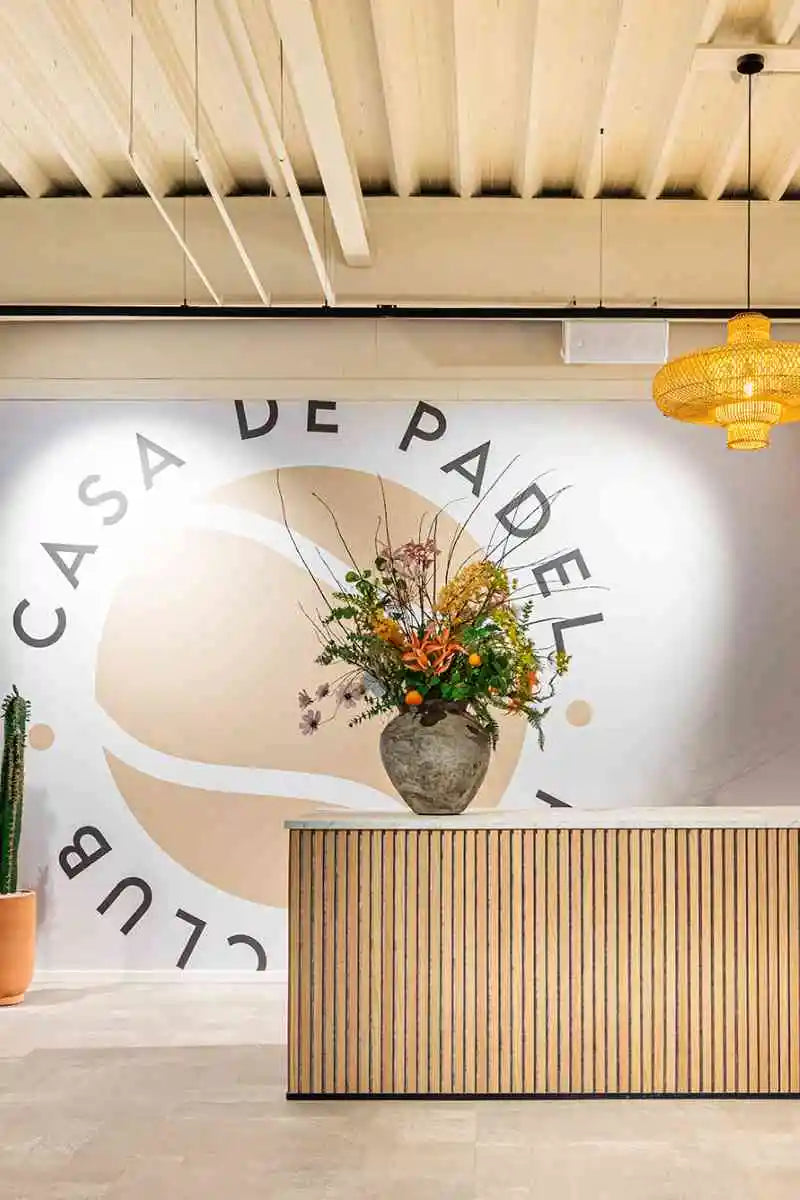 winkelinrichting op maat met houten balie, lattenfront, bloemenvaas en modern clubinterieur met wandlogo