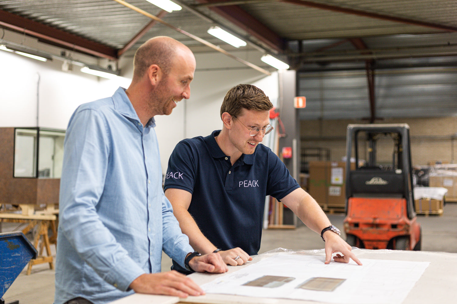 Medewerkers van PEACK met een werktekening in de werkplaats