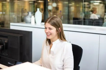 winkelinrichting op maat met moderne receptiebalie, medewerker achter balie en minimalistisch kantoorinterieur