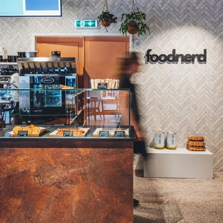 winkelinrichting op maat met roestkleurige toonbank, glazen vitrine met broodproductpresentatie en modern speciaalzaak winkelinterieur met visgraat tegelwand