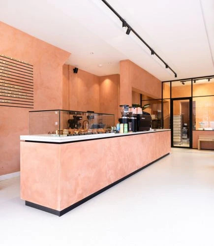 winkelinrichting op maat met lange roze toonbank, glazen vitrine, koffiemachines en modern patisserie winkelinterieur