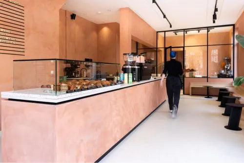 winkelinrichting op maat met lichtroze stucwerk toonbank, glazen vitrine voor broodpresentatie en modern bakkerij winkelinterieur