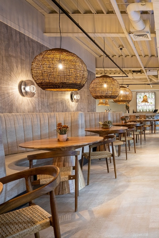 Maatwerk wandbank met houten tafels en sfeerverlichting in een moderne sportkantine en lounge van een padelclub.