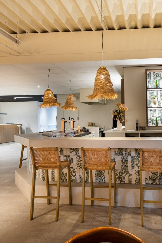 Maatwerk bar met rotan barkrukken en sfeerverlichting in een moderne sportkantine van een commerciële padelclub.