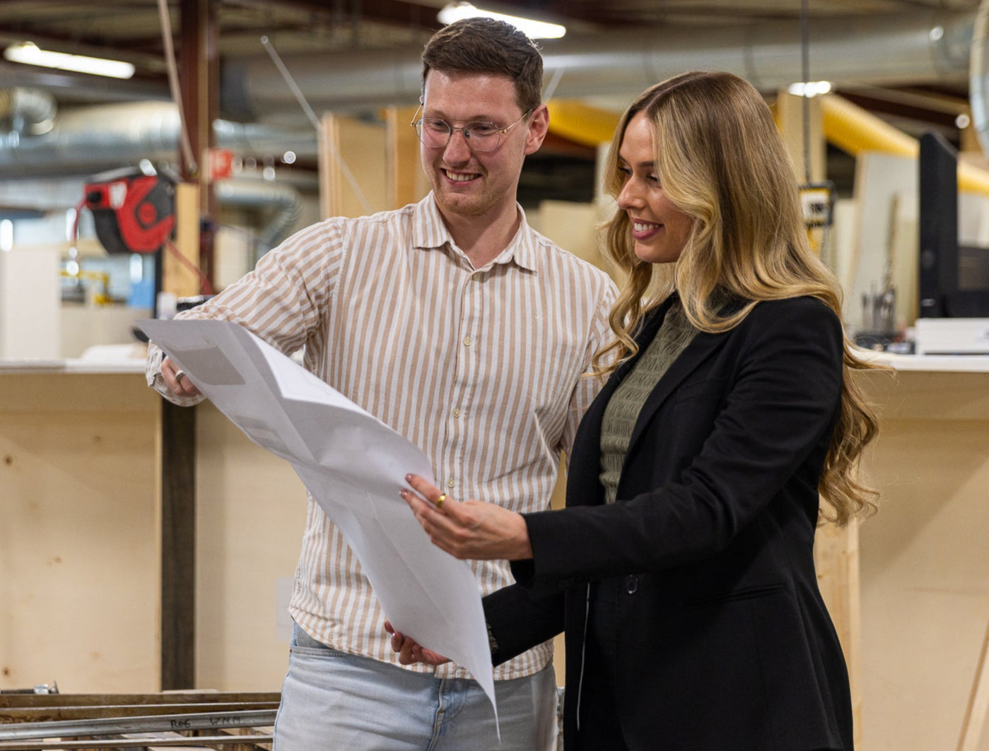 Twee medewerkers van PEACK in de werkplaats met een werktekening