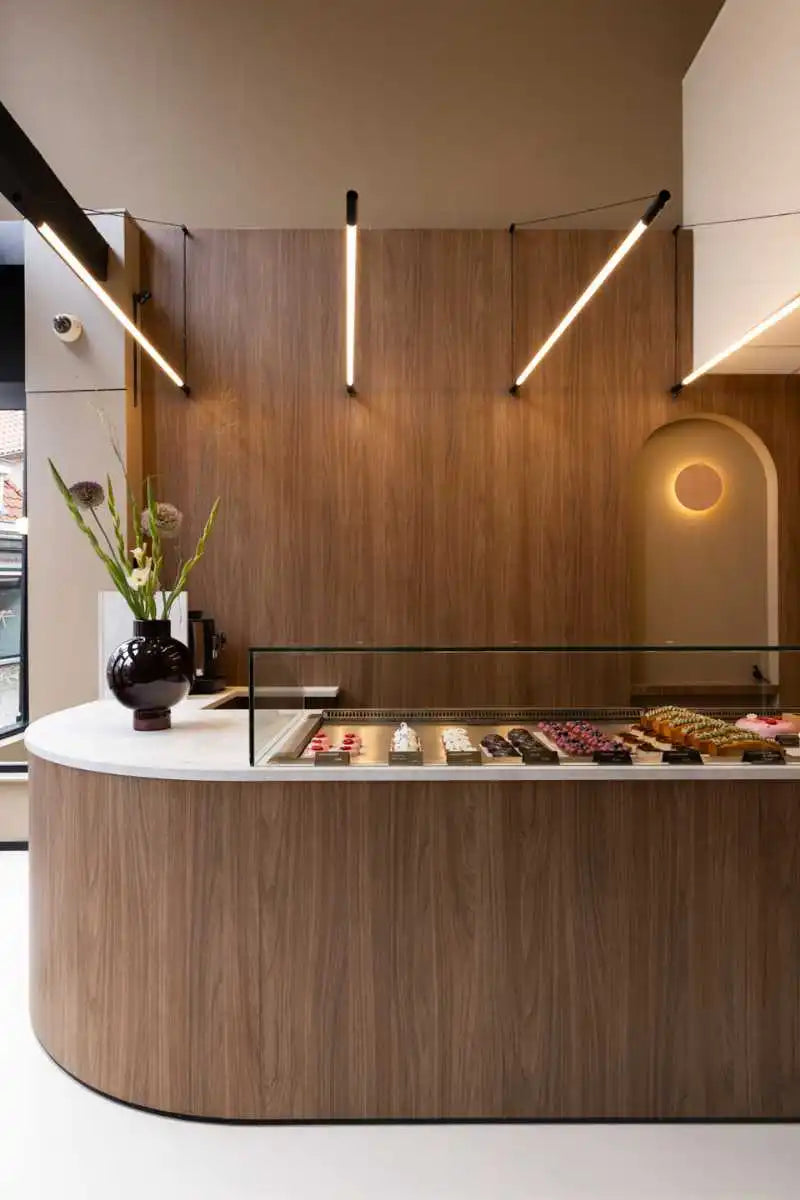 winkelinrichting op maat met ronde houten toonbank, glazen vitrine en patisserie productpresentatie in modern winkelinterieur