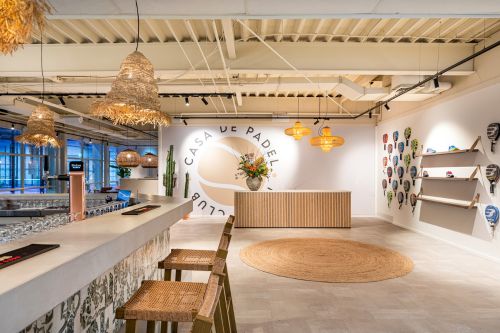 Bar en ontvangstbalie met maatwerkinterieur in een moderne padelclub met clubhuis en sportkantine inrichting.