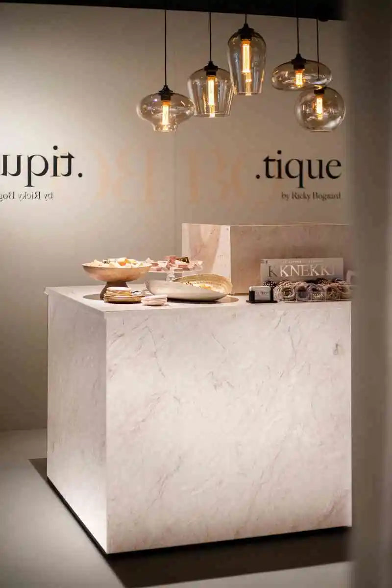winkelinrichting op maat met marmeren toonbank, productpresentatie en hanglampen in boutique winkelinterieur
