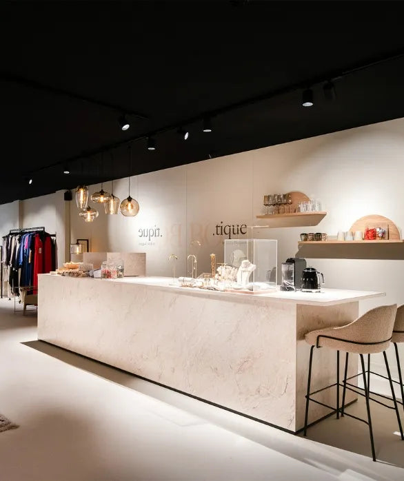 winkelinrichting op maat met lange marmeren toonbank, productpresentatie, design verlichting en modern boutique winkelinterieur