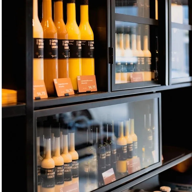 winkelinrichting op maat met zwarte kast met glazen deuren, flessenproductpresentatie en prijskaartjes in modern retail winkelinterieur