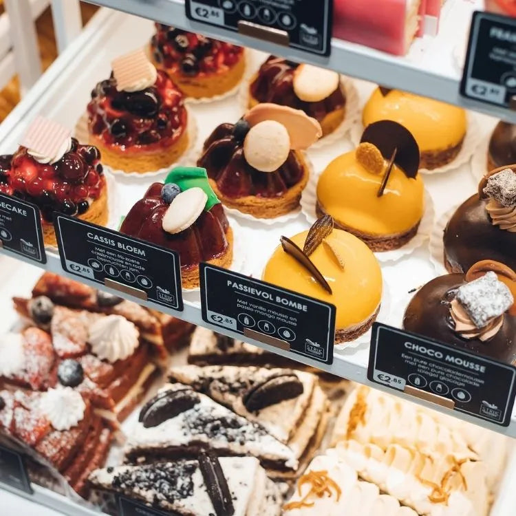 winkelinrichting op maat met patisserie productpresentatie in glazen vitrine met zwarte prijskaartjes en desserts in modern bakkerij winkelinterieur