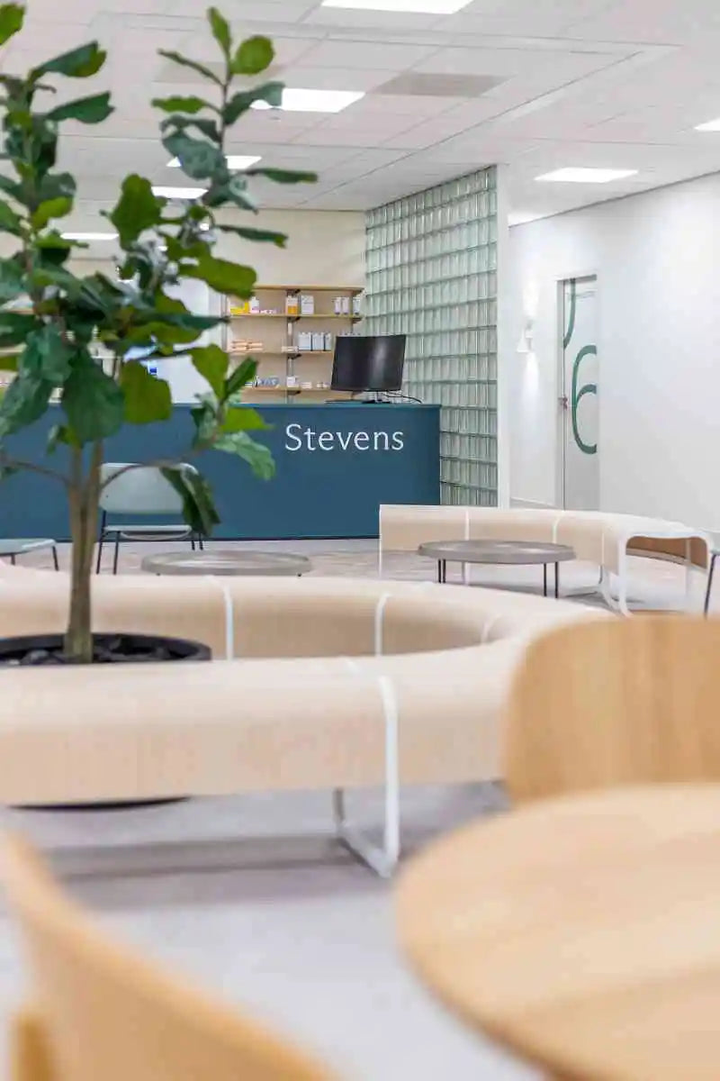 winkelinrichting op maat met apotheekbalie, wachtruimte met zitbanken en modern zorginterieur