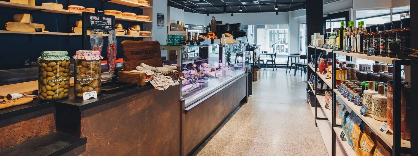 winkelinrichting op maat met roestkleurige toonbank, glazen kaasvitrine, wandplanken met kaasproductpresentatie en moderne speciaalzaak winkelstellingen