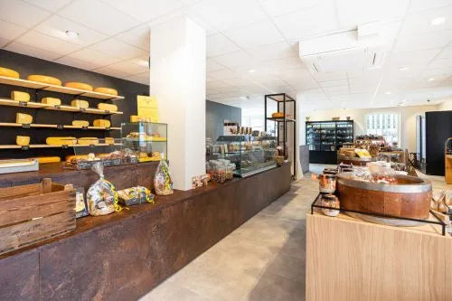 winkelinrichting op maat met roestkleurige toonbank, kaasproductpresentatie op wandplanken en modern kaaswinkel winkelinterieur