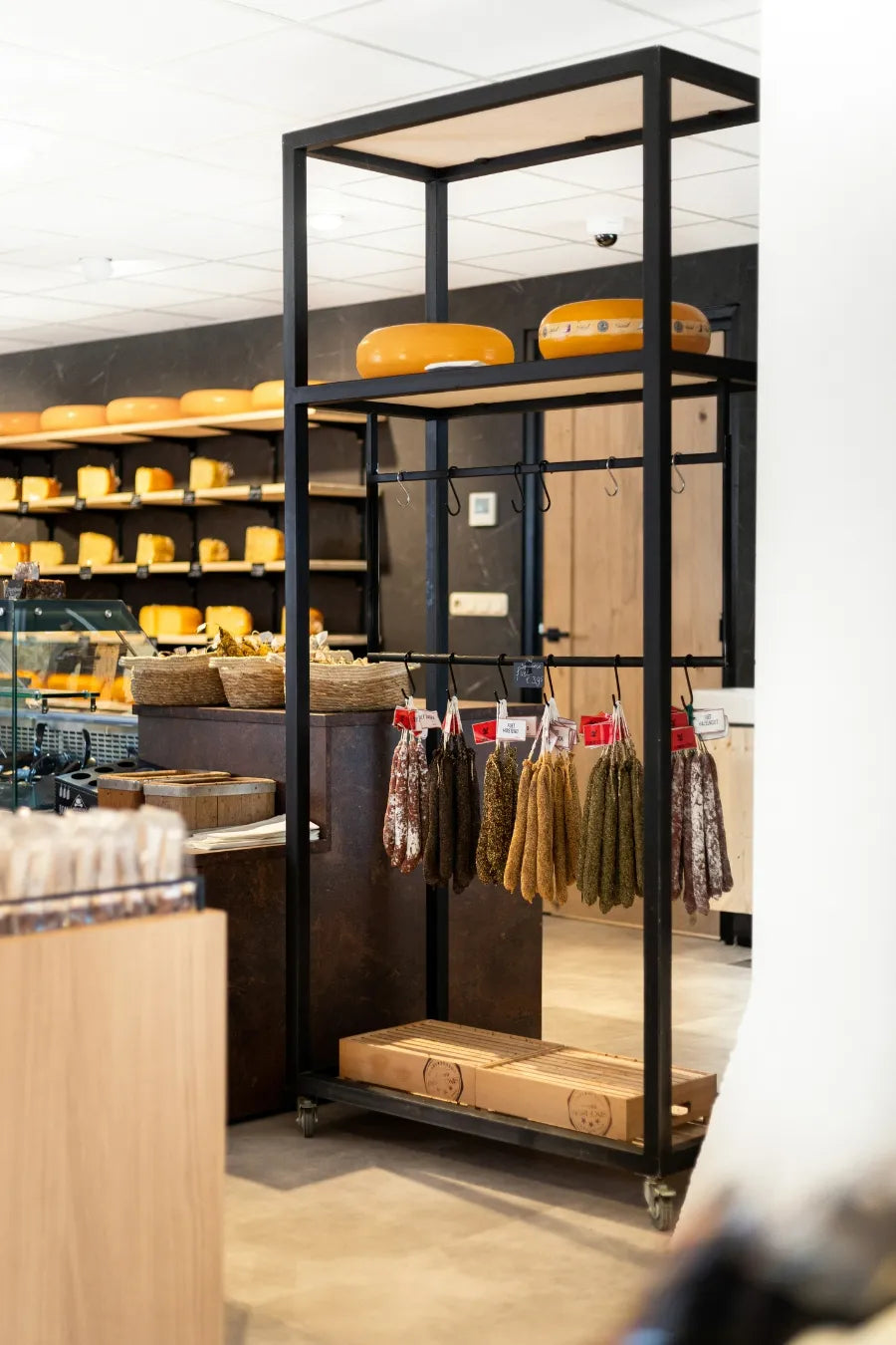winkelinrichting op maat met zwarte metalen winkelstelling, hangende worstproductpresentatie en kaaswinkel winkelinterieur