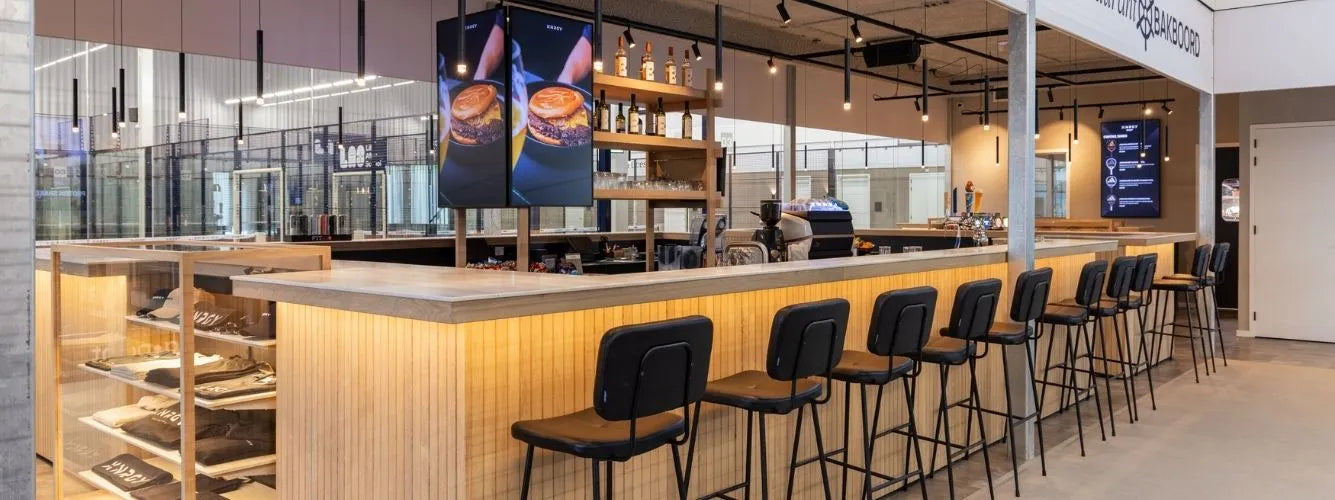 Maatwerk bar met houten afwerking en barkrukken in een moderne sportkantine van een commerciële padelclub.