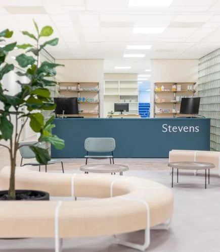 winkelinrichting op maat met blauwgroene balie, wachtruimte met ronde zitbank en modern apotheek winkelinterieur met lichte materialen