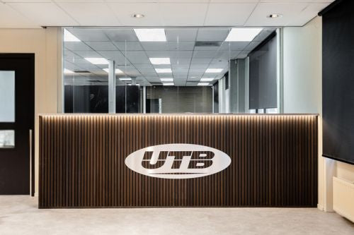 Moderne receptiebalie met houten lattenfront en geïntegreerde LED-verlichting, voorzien van een bedrijfslogo, geplaatst in een strakke kantooromgeving met glaswanden en systeemplafond.